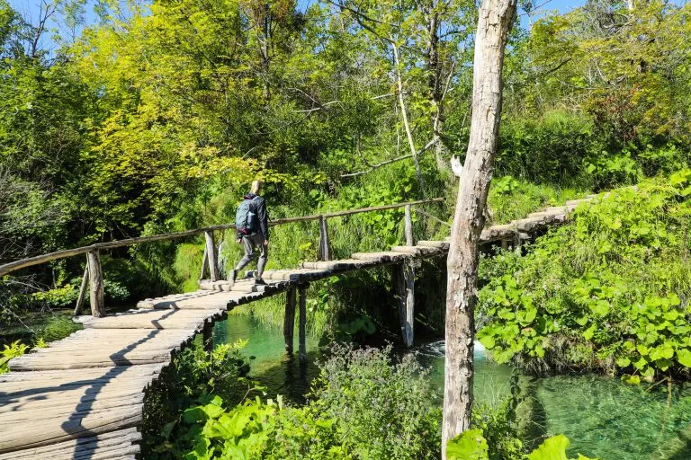Senderista rubia caminando por los senderos de madera del Parque Nacional de Plitvice