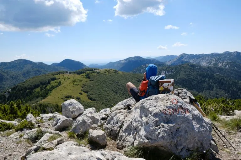 Der schöne Bergpfad Premuziceva Staza, Nationalpark Velebit, Dinarisches Gebirge, Kroatien. Silhouette eines ruhenden Touristen auf dem Gipfel Veliki Zavizan.